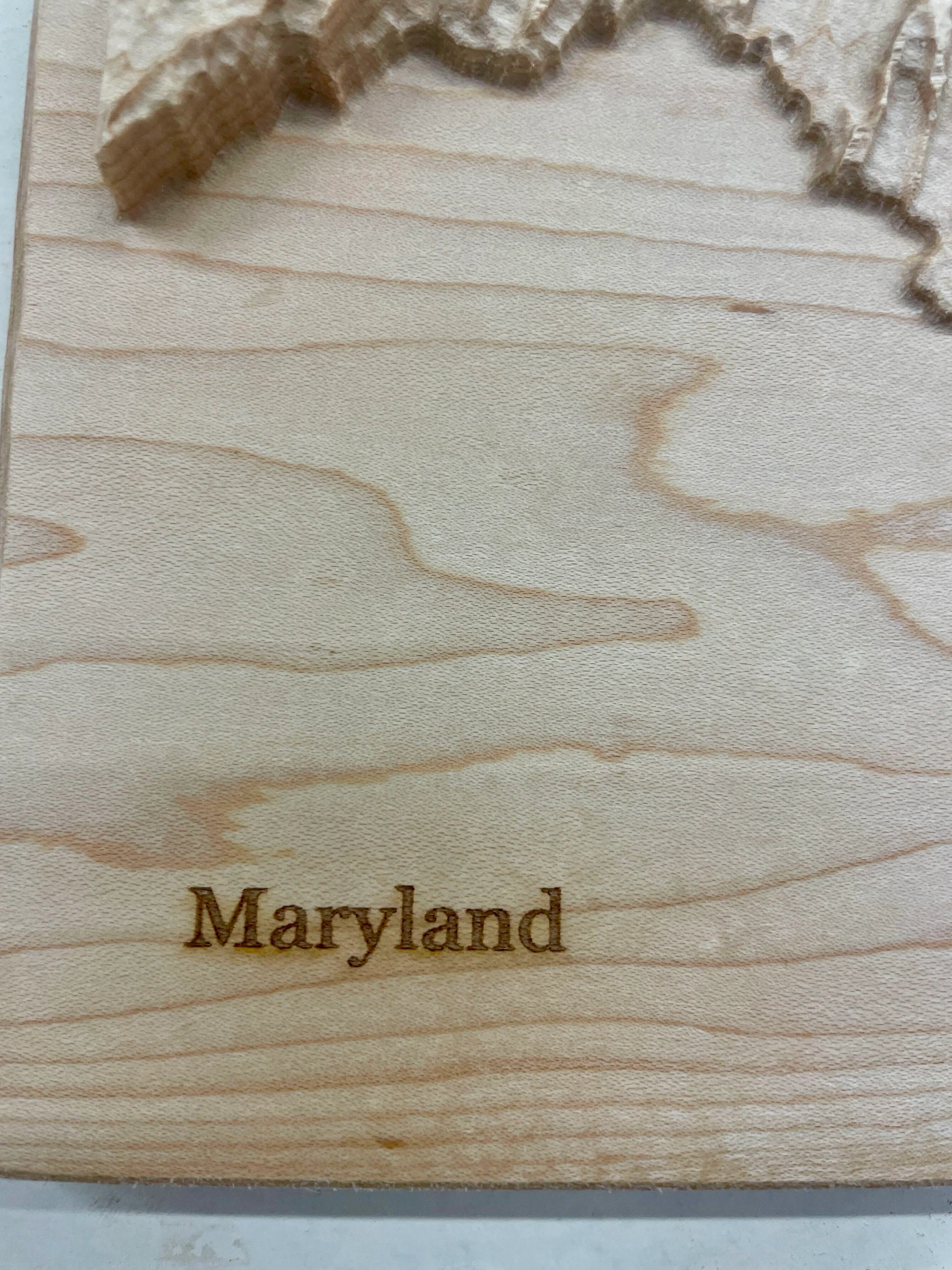 Wooden relief map of Maryland with 'Maryland' engraved on it.