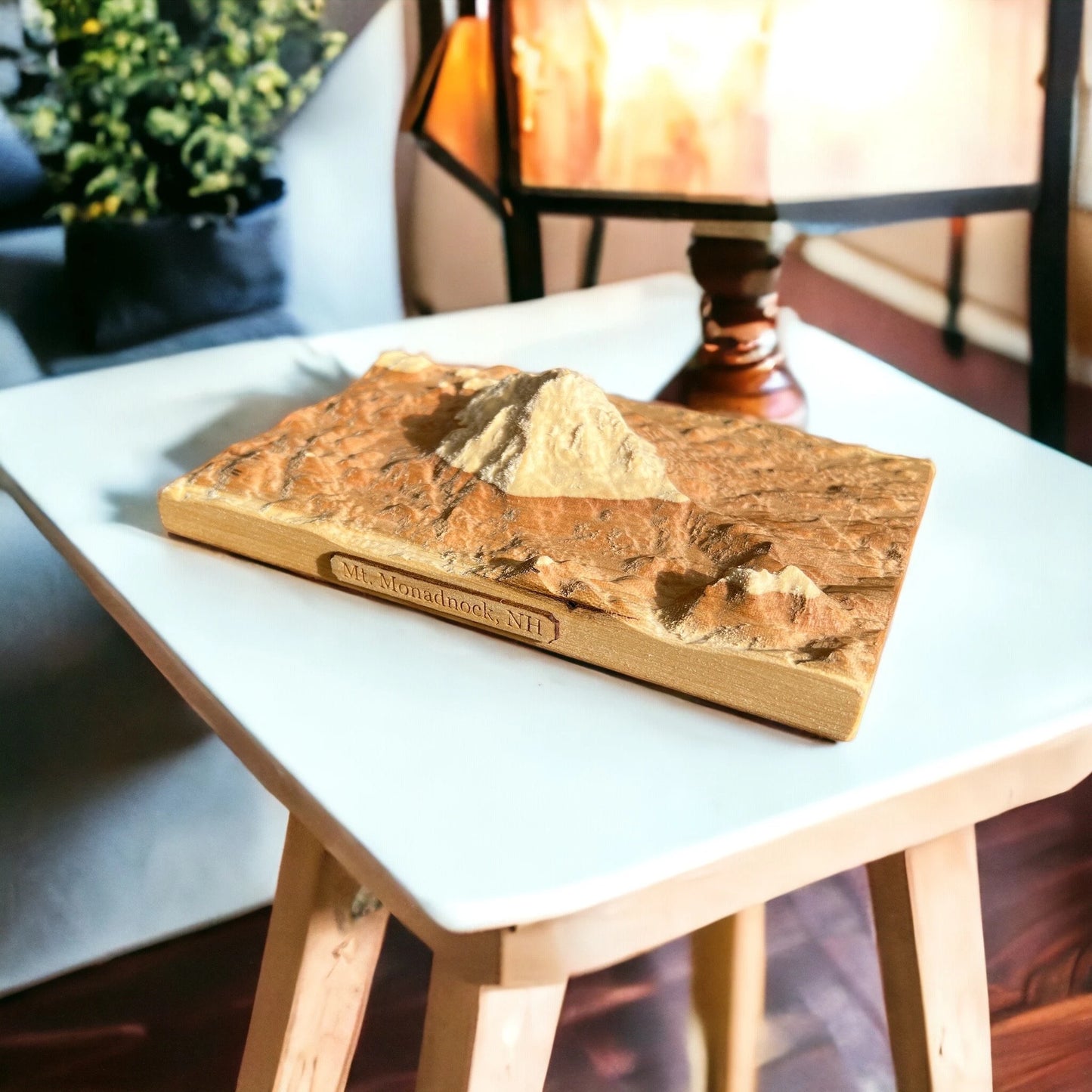 Wooden Mt Monadnock mountain topo map carving on a white table with a blurred indoor background