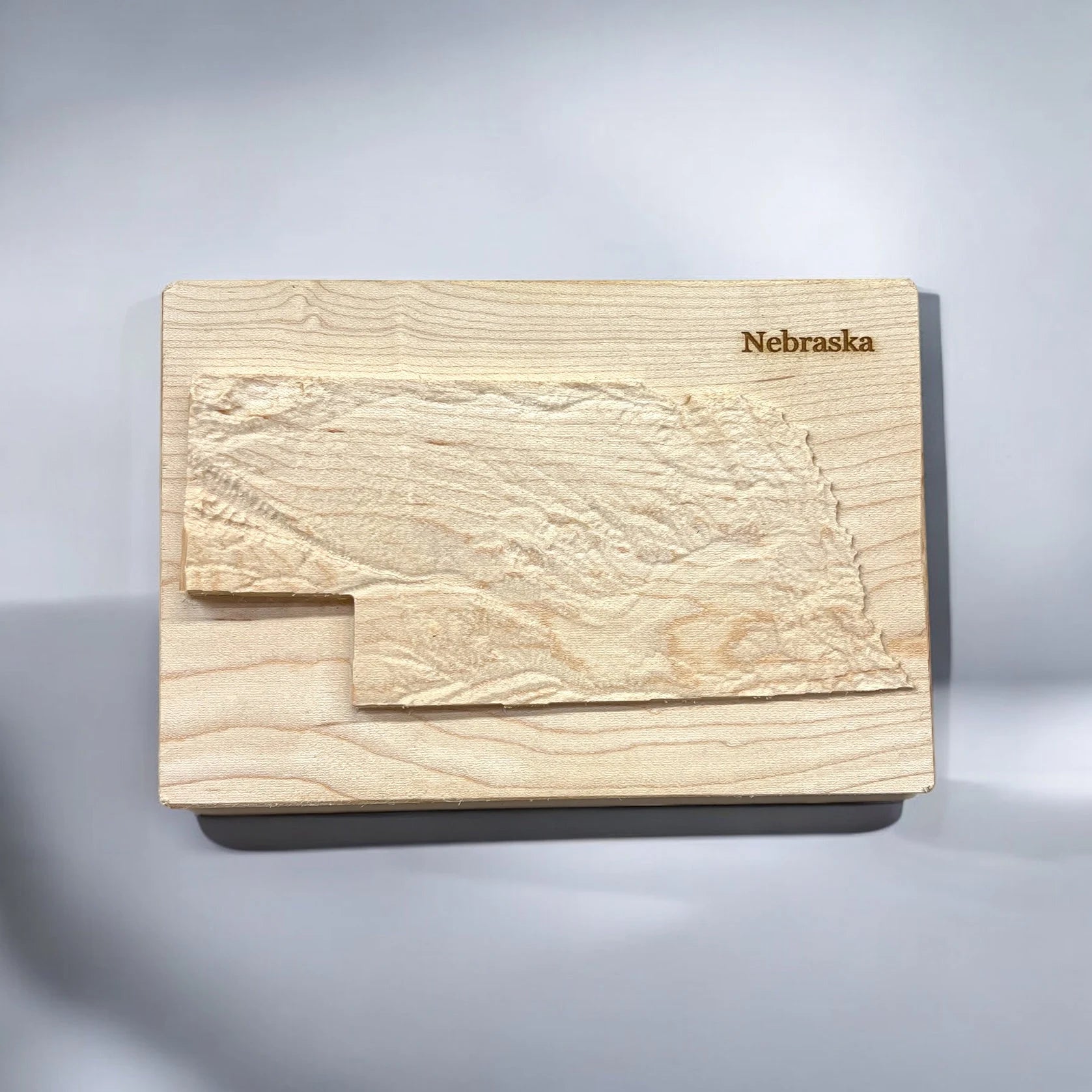Carved wooden topographical map of Nebraska mounted on a gray background