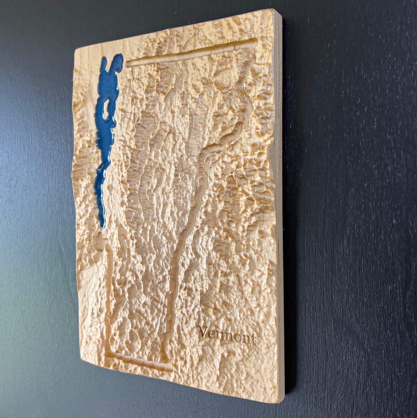 Vermont state map with 3D topographic detail carved in wood.