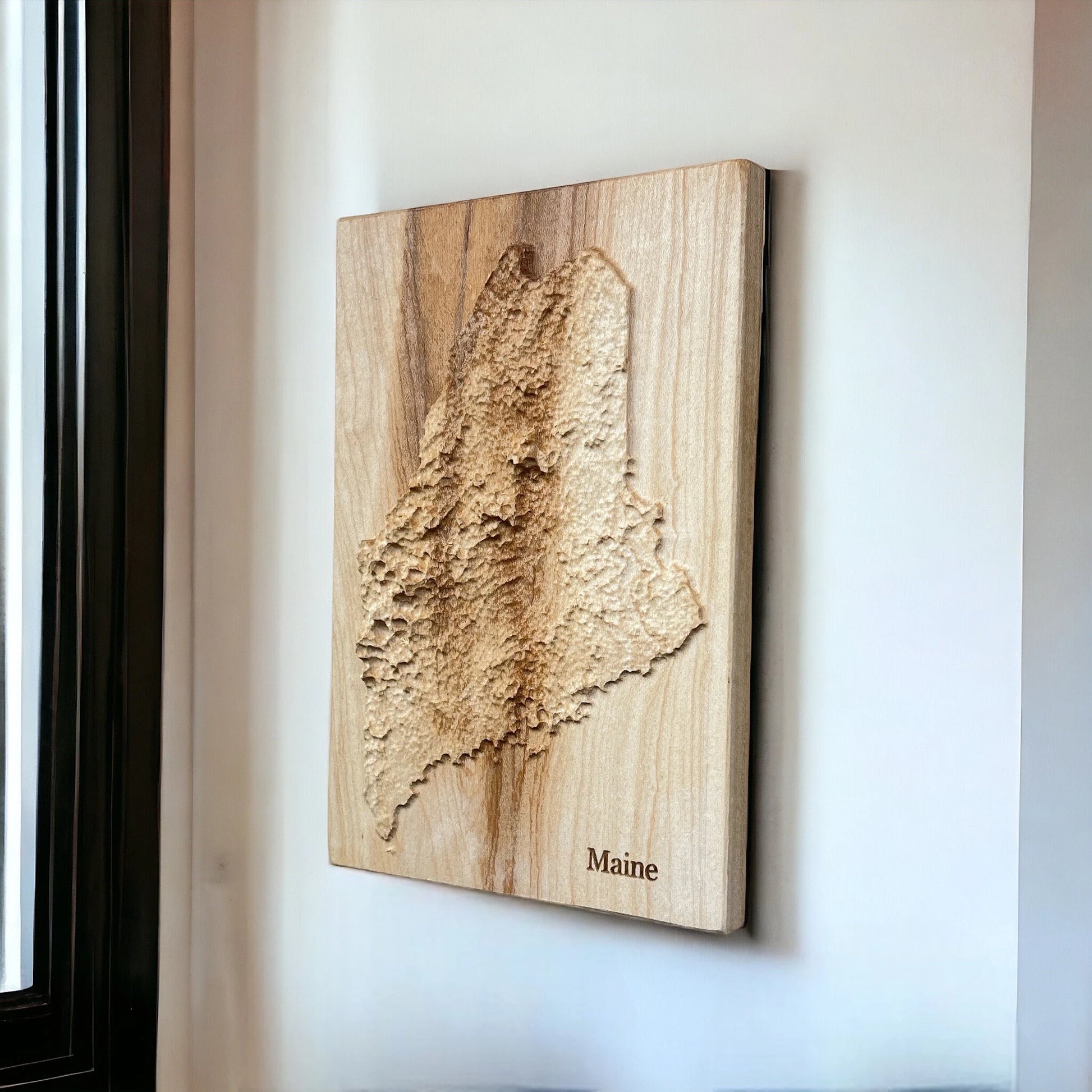 Wooden 3d relief map of Maine on a white wall