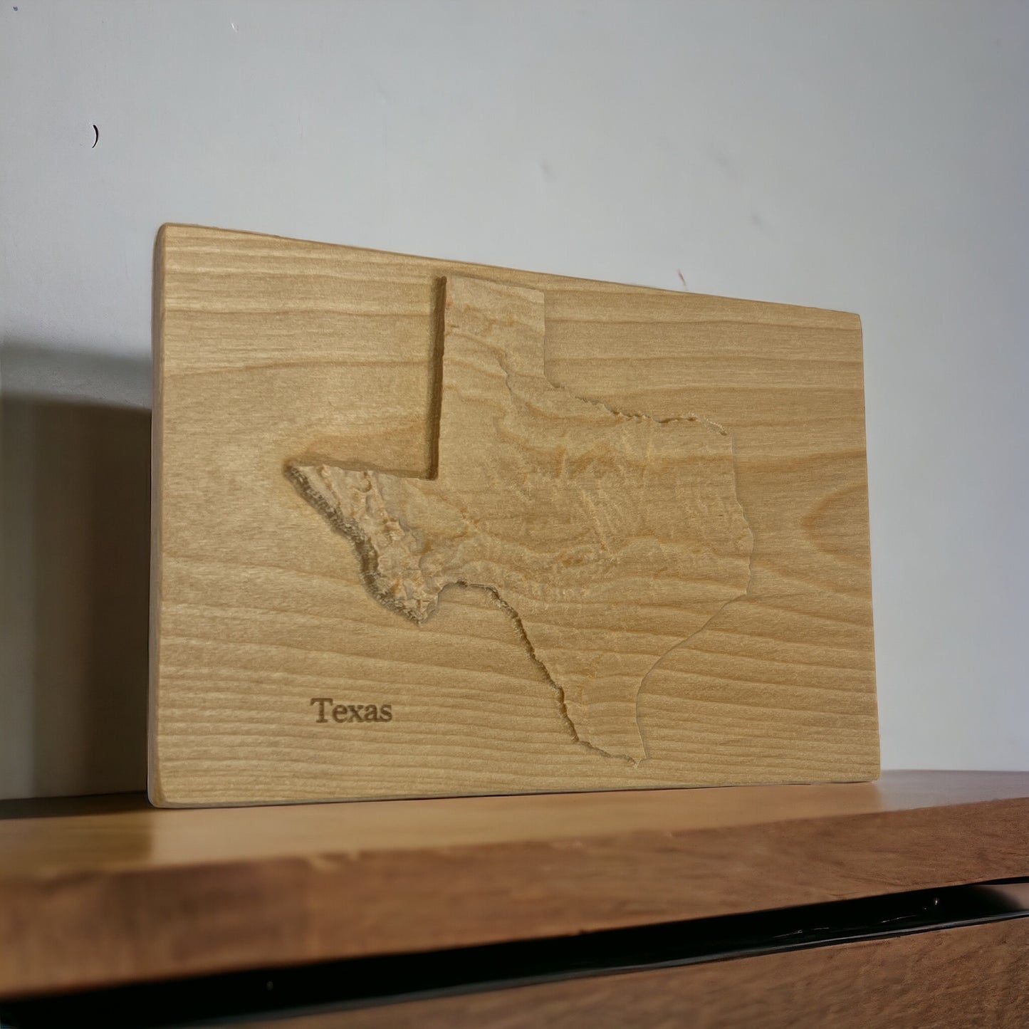 A 3D topographic wooden map of Texas, made from locally-sourced wood, with a carving that captures the shape and relief of the landscape.