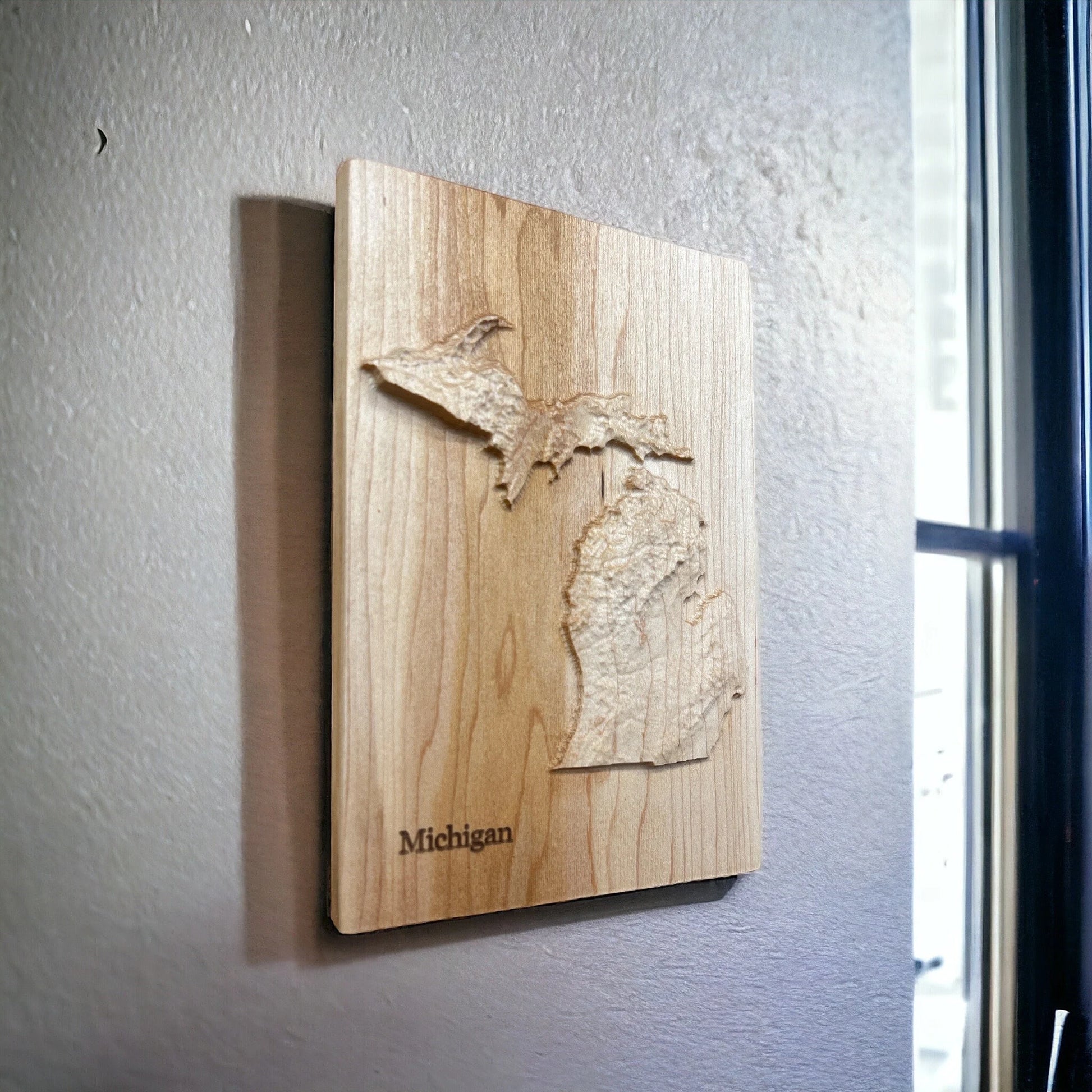 Wooden wall art of Michigan's topography on a gray wall.