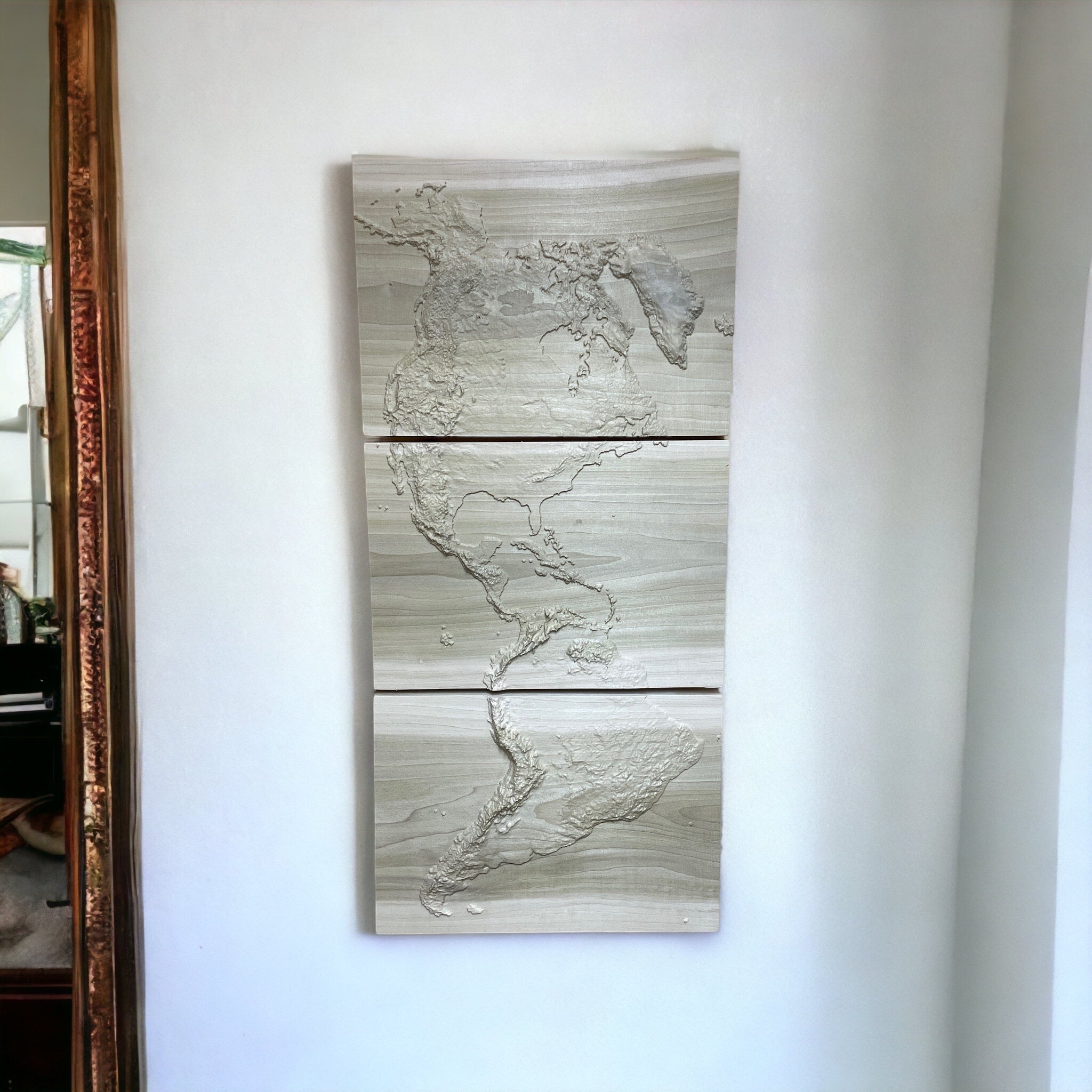 3-panel 3d wood carved topo map of the americas hanging on a white wall