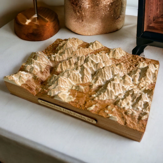 A wooden 3D topographic map of the Adirondack Mountains with raised relief depicting mountain ranges.