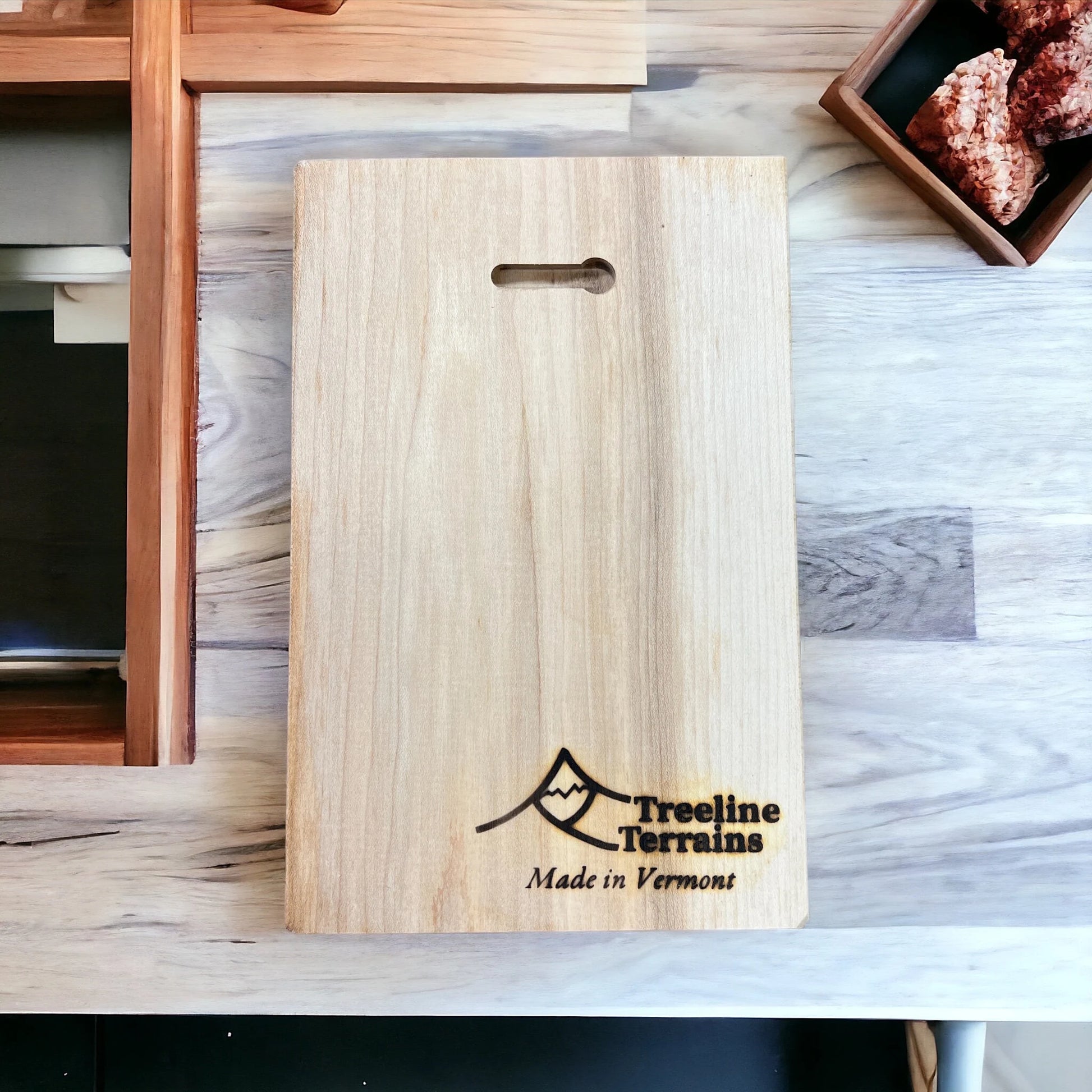 Wooden map backside with wall hanging slot detail with 'TreeLine Terrains Made in Vermont' engraving on a kitchen counter.