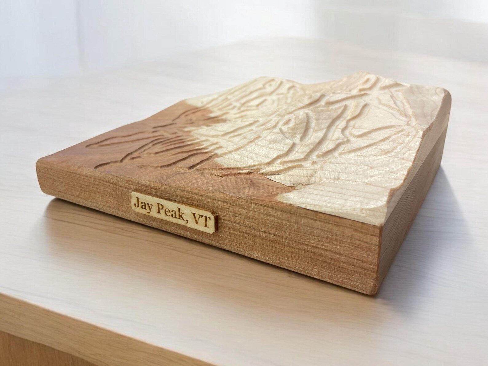 Wooden model of a mountain with 'Jay Peak, VT' engraved on it