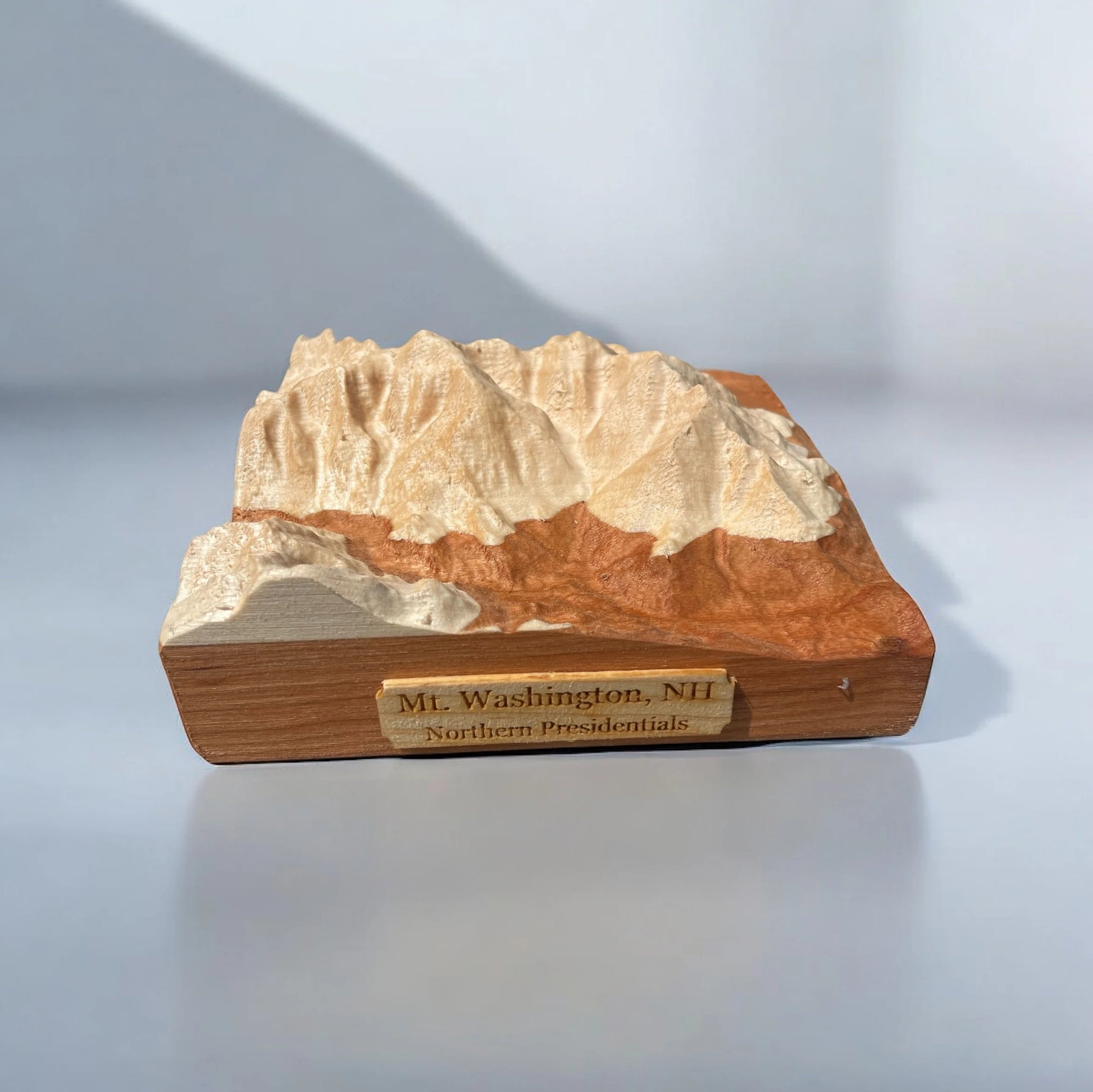 Wooden model of a mountain range with 'Mt. Washington, NH' engraved on a white background