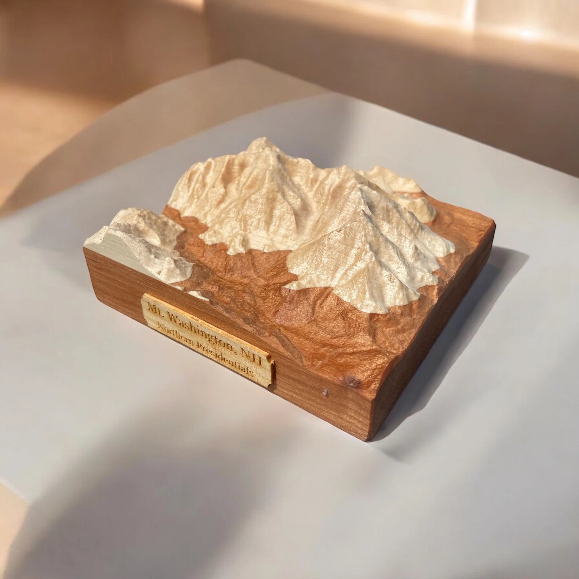 Wooden model of mt washington mountain with a plaque on a white surface