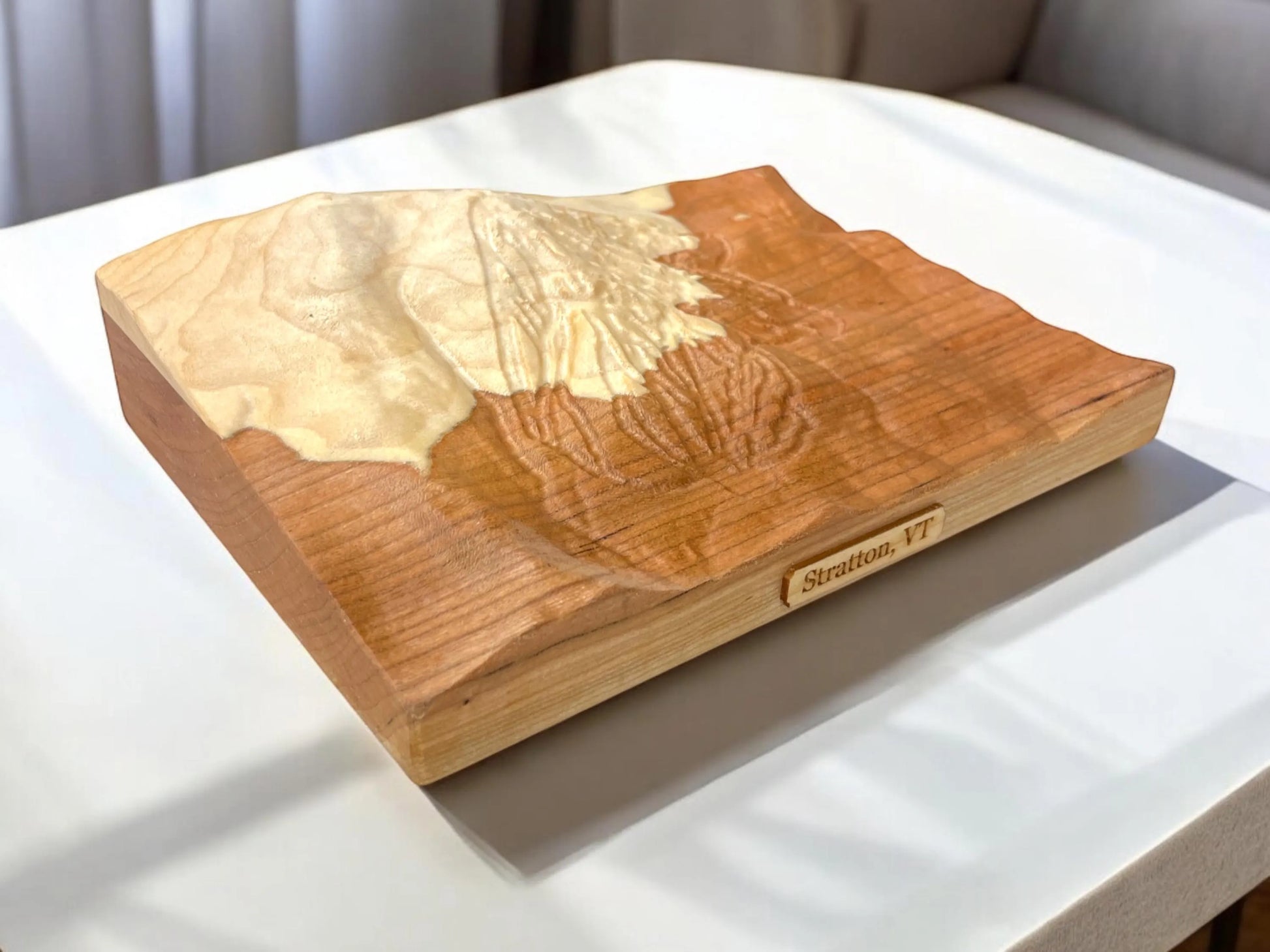 Wood-carved 3D topographic map of Stratton Mountain trails on a white surface