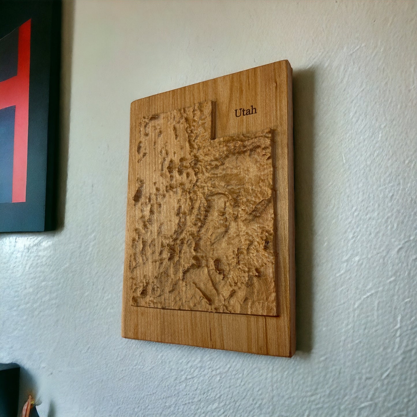 A wood carved relief map of Utah, mounted on a wall.