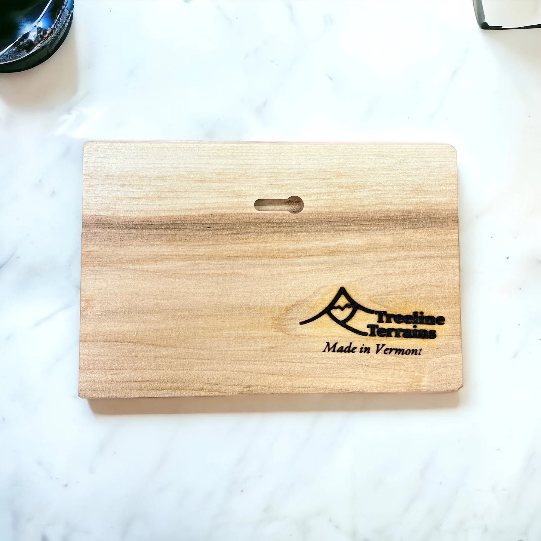 Wooden map backside with 'TreeLine Terrains Made in Vermont' engraving and wall hanging detail on a white surface