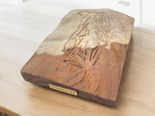 A wooden 3D relief ski map of Bromley Mountain, featuring topographic details and made with cherry and maple woods. The map is displayed on a wooden surface.