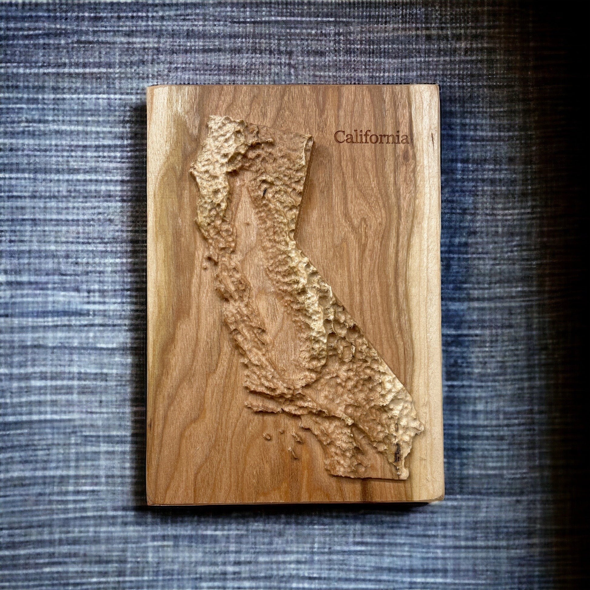 Wooden relief map of California on a textured blue background