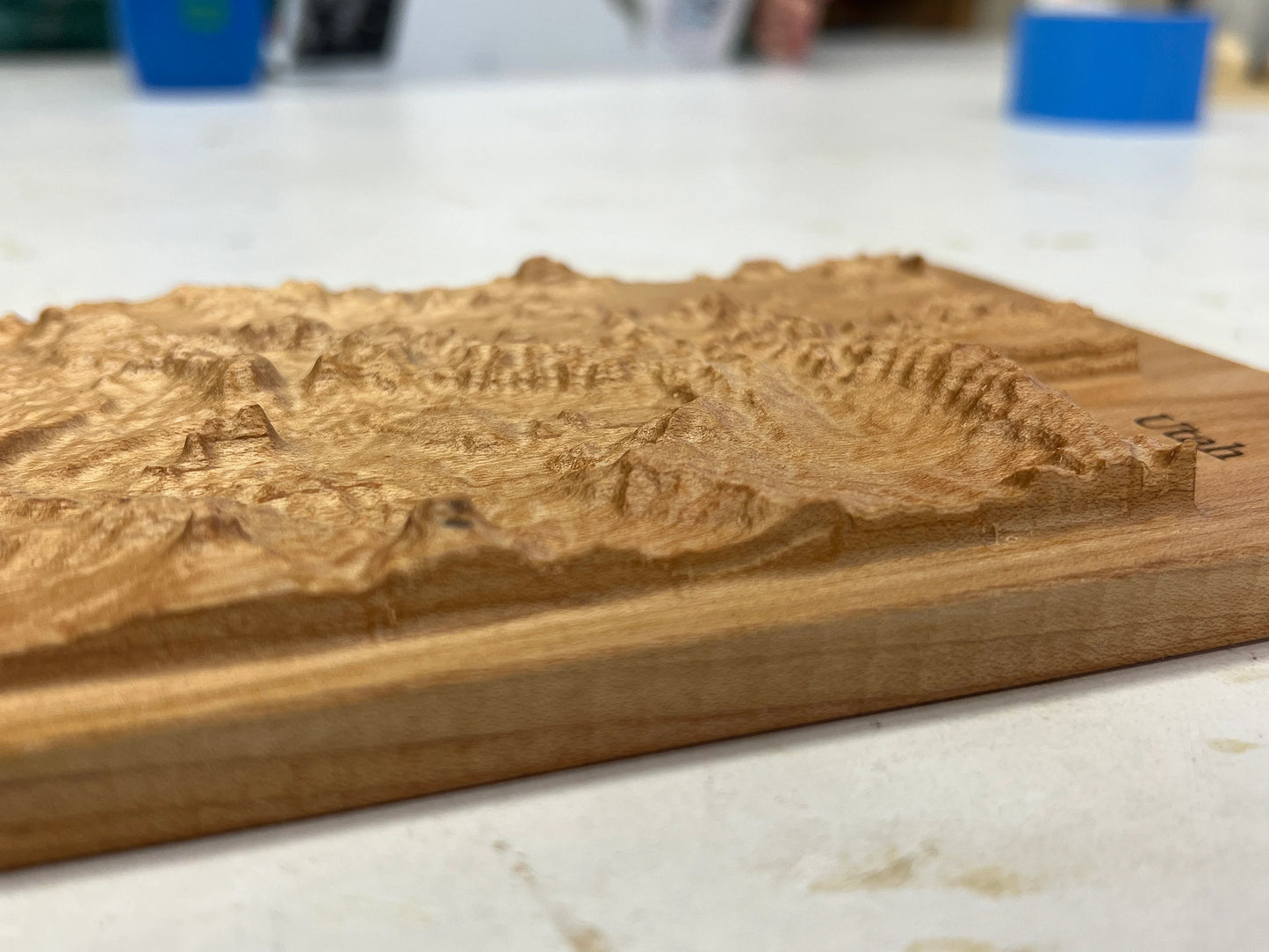 Wooden relief map of the state of utah landscape on a plaque on a light countertop