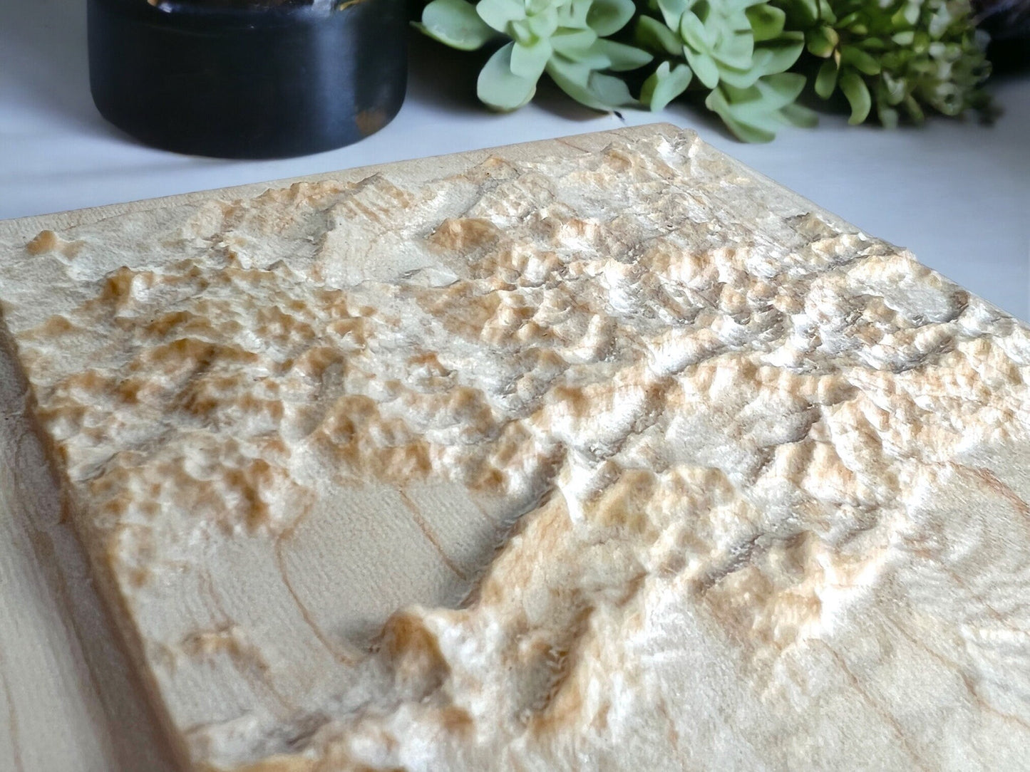 detail of the colorado mountains on a wood-carved topographic map  on a light background
