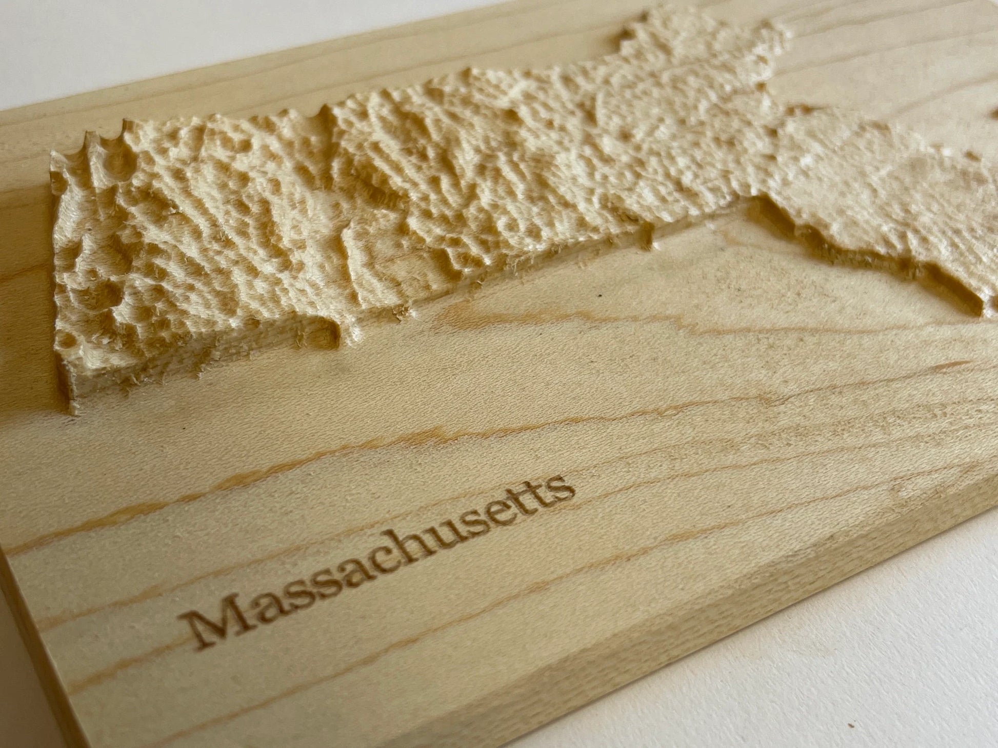 Wooden relief map of Massachusetts with 'Massachusetts' engraved on it.