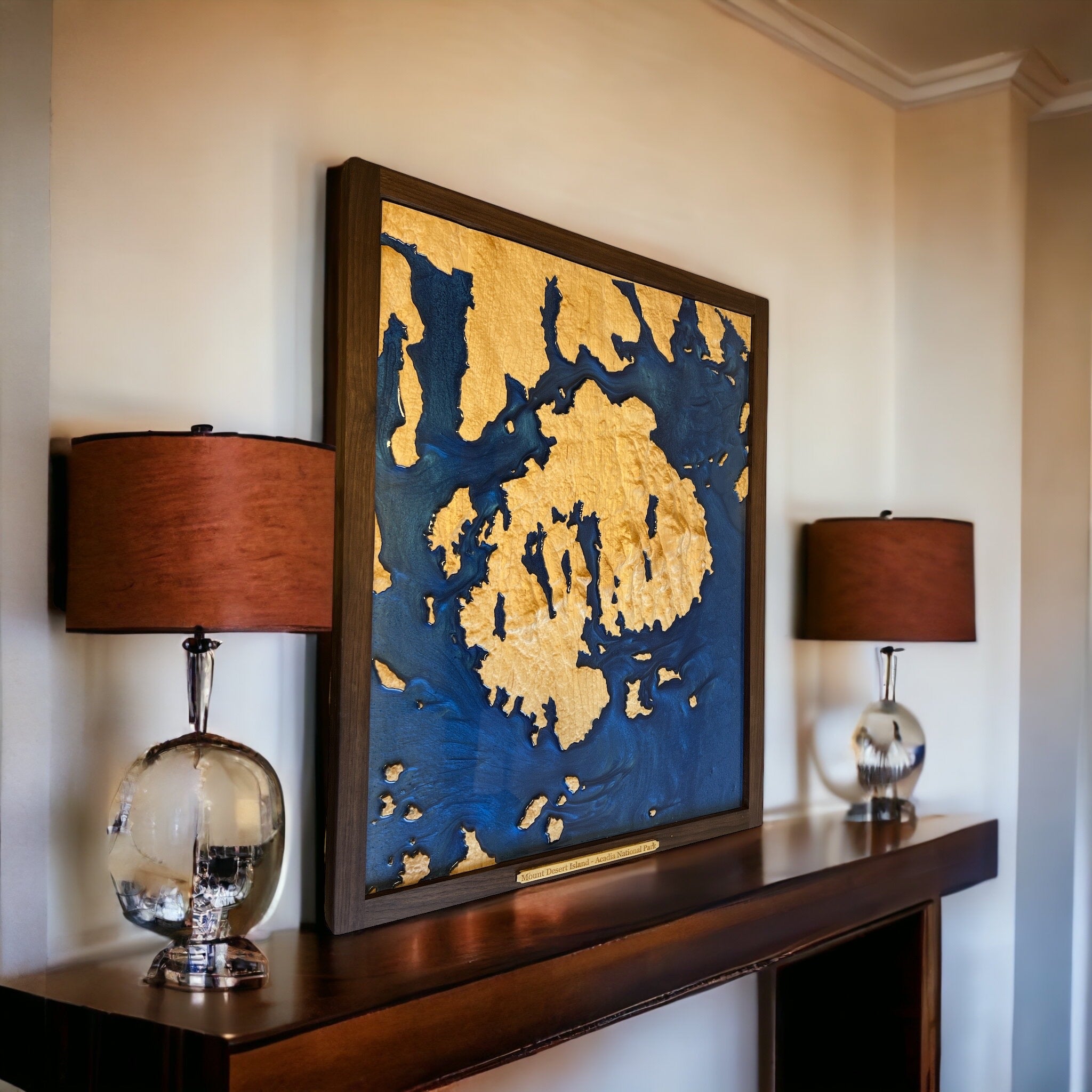large map of acadia national park and desert island on a shelf with 2 lamps and a white wall