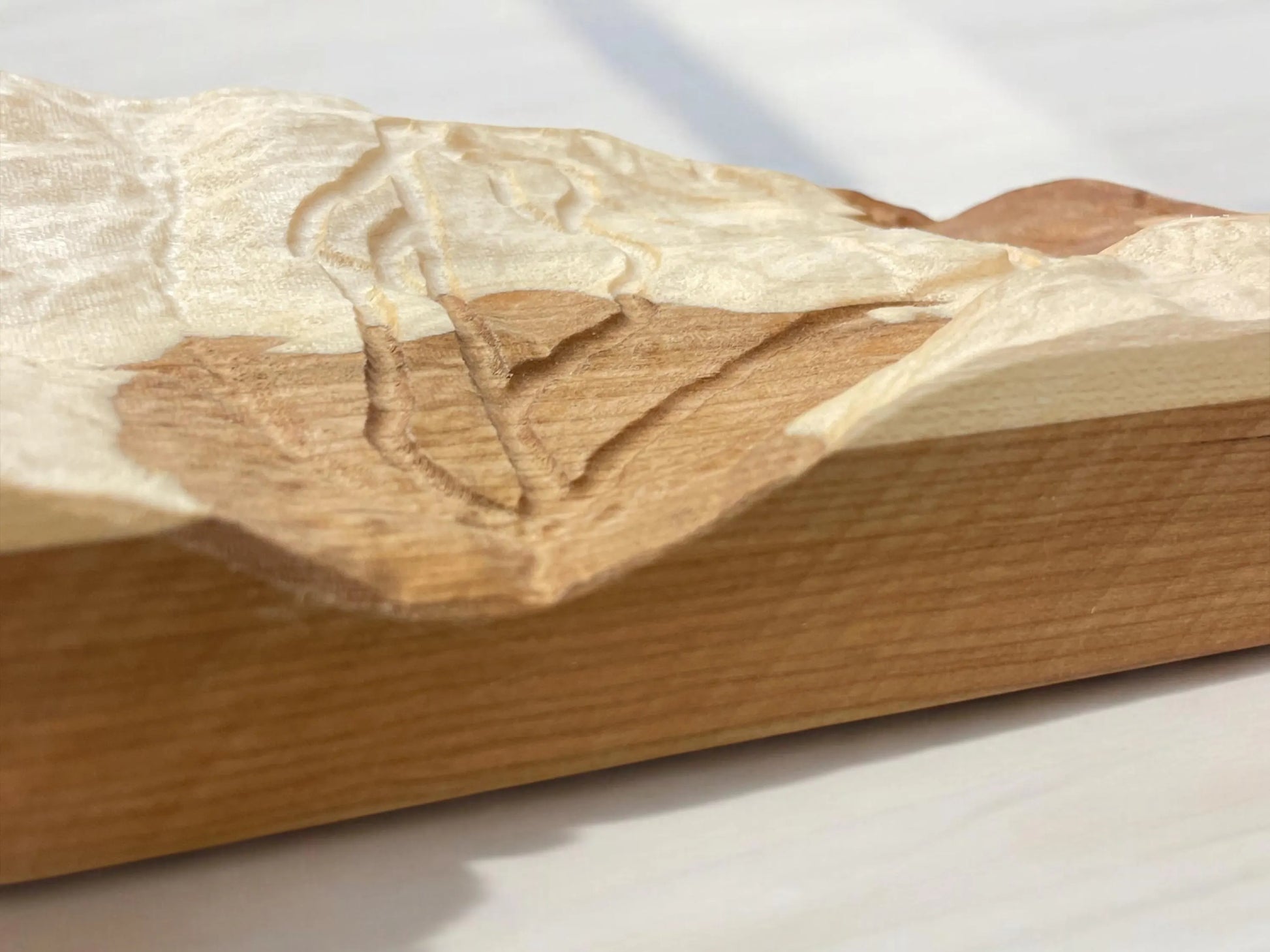 Wooden block with intricate carving details of the Middlebury Snow Bowl ski mountain on a light background