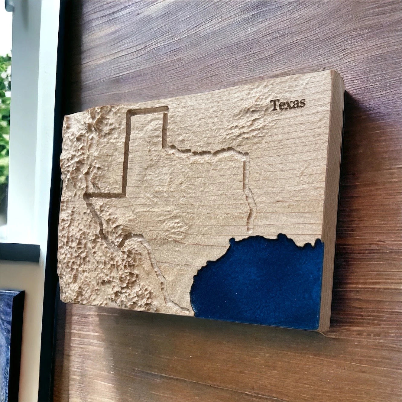 Wooden plaque with a textured map of Texas on a wooden surface