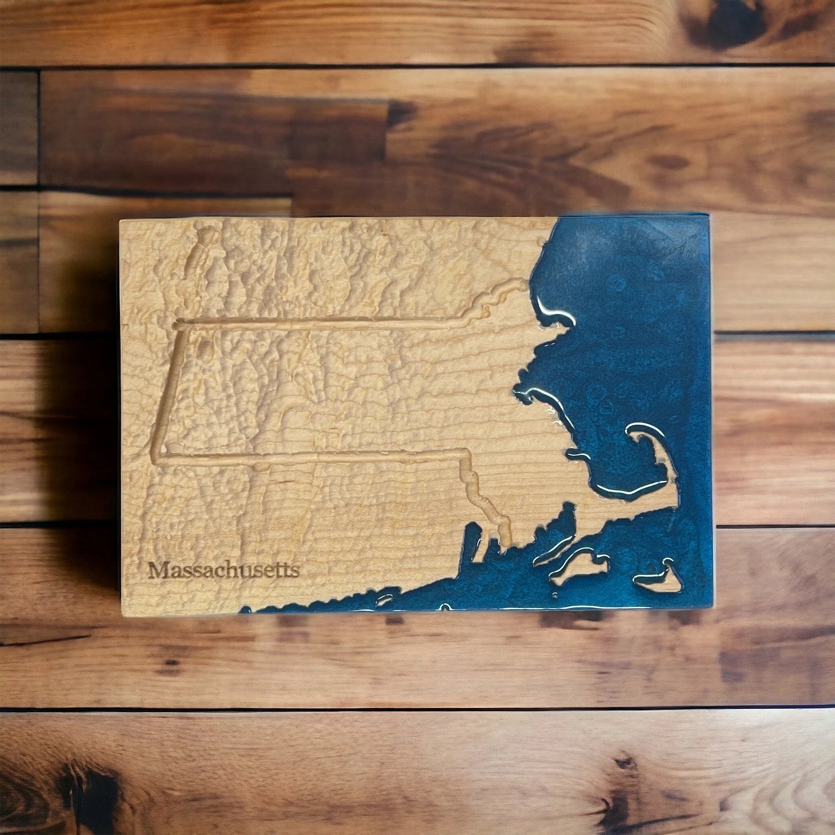 Wooden plaque with engraved map of Massachusetts on a wooden surface