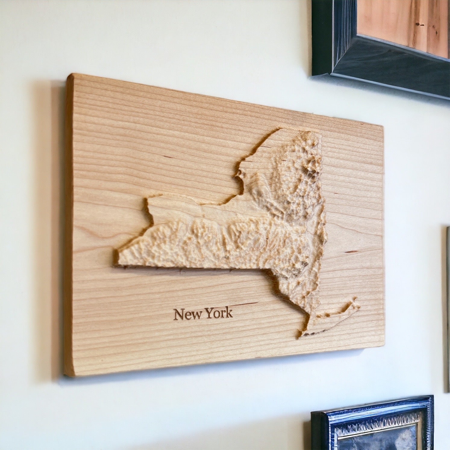 A wood carved relief map of New York state, mounted on a wall.