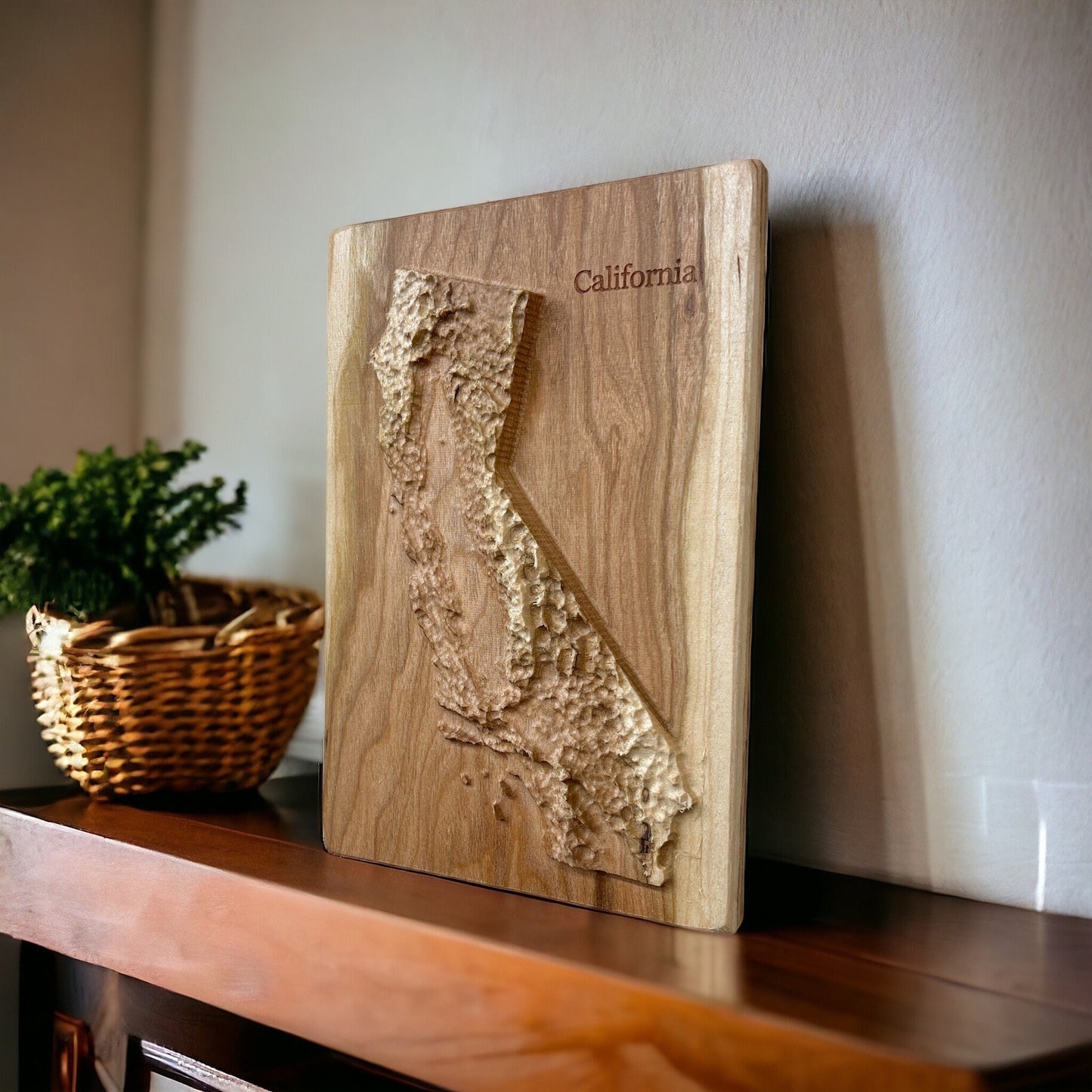 Wooden plaque with a 3D map of California on a wooden shelf and white wall