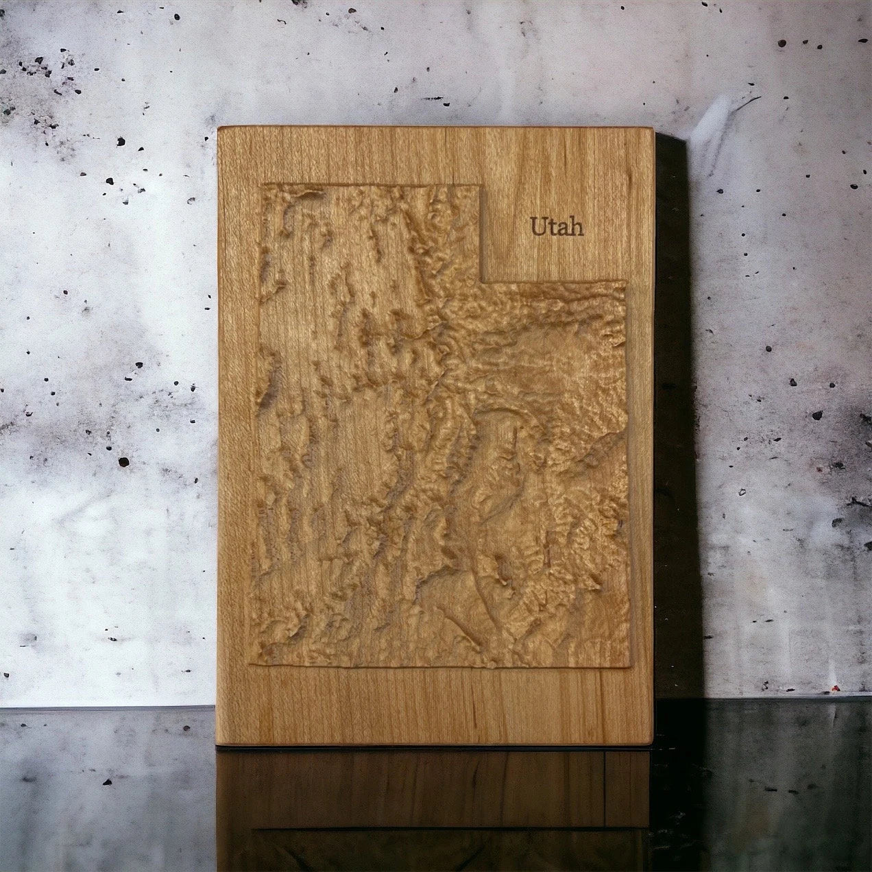 Wooden topographic map of Utah on a concrete surface