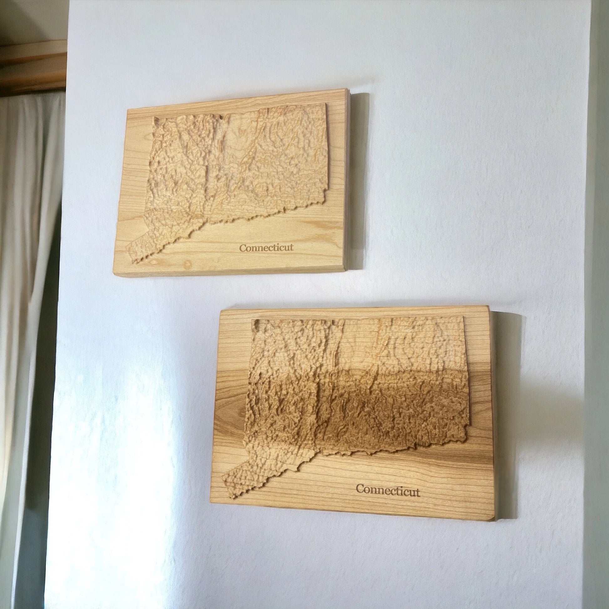 Two wooden maps of Connecticut on a white wall.